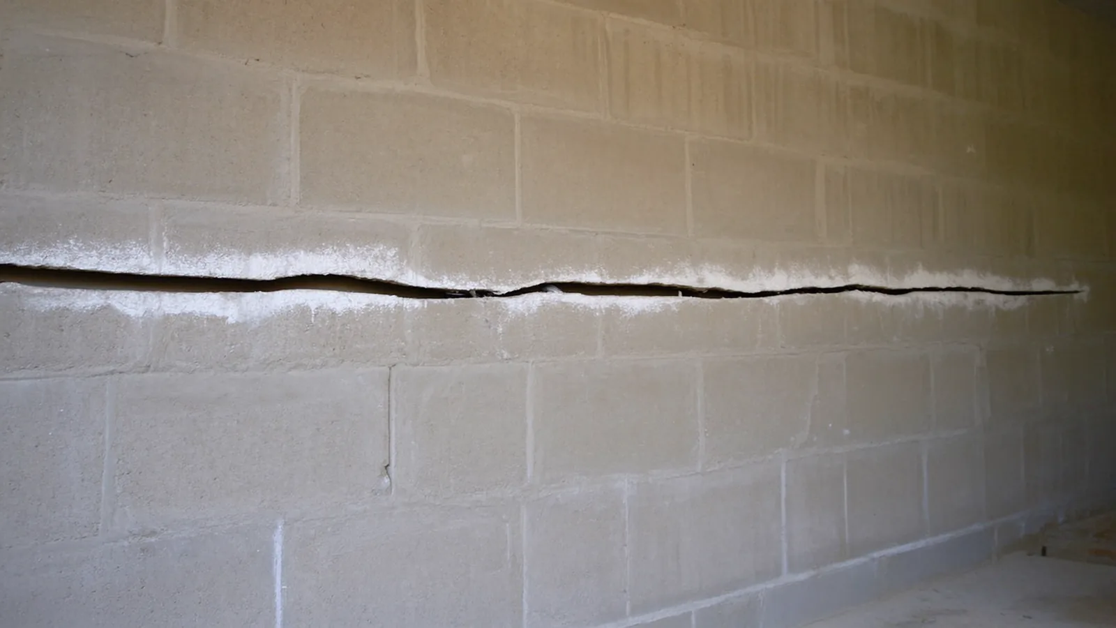 Horizontal crack running across a concrete block basement wall in a Knoxville Tennessee home showing inward bowing