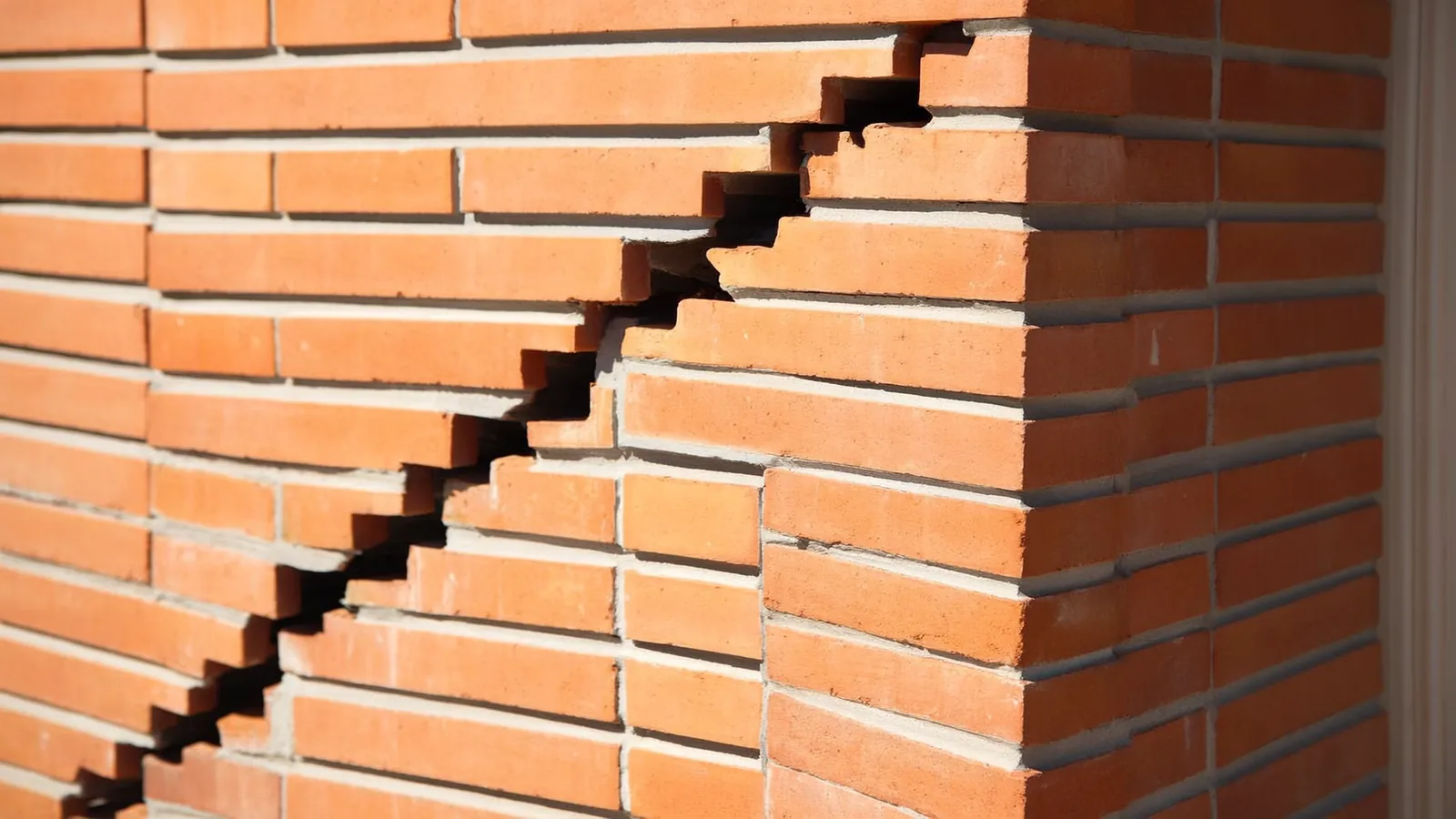 Stair-step cracks running diagonally through the mortar joints of a brick foundation wall on a Knoxville home